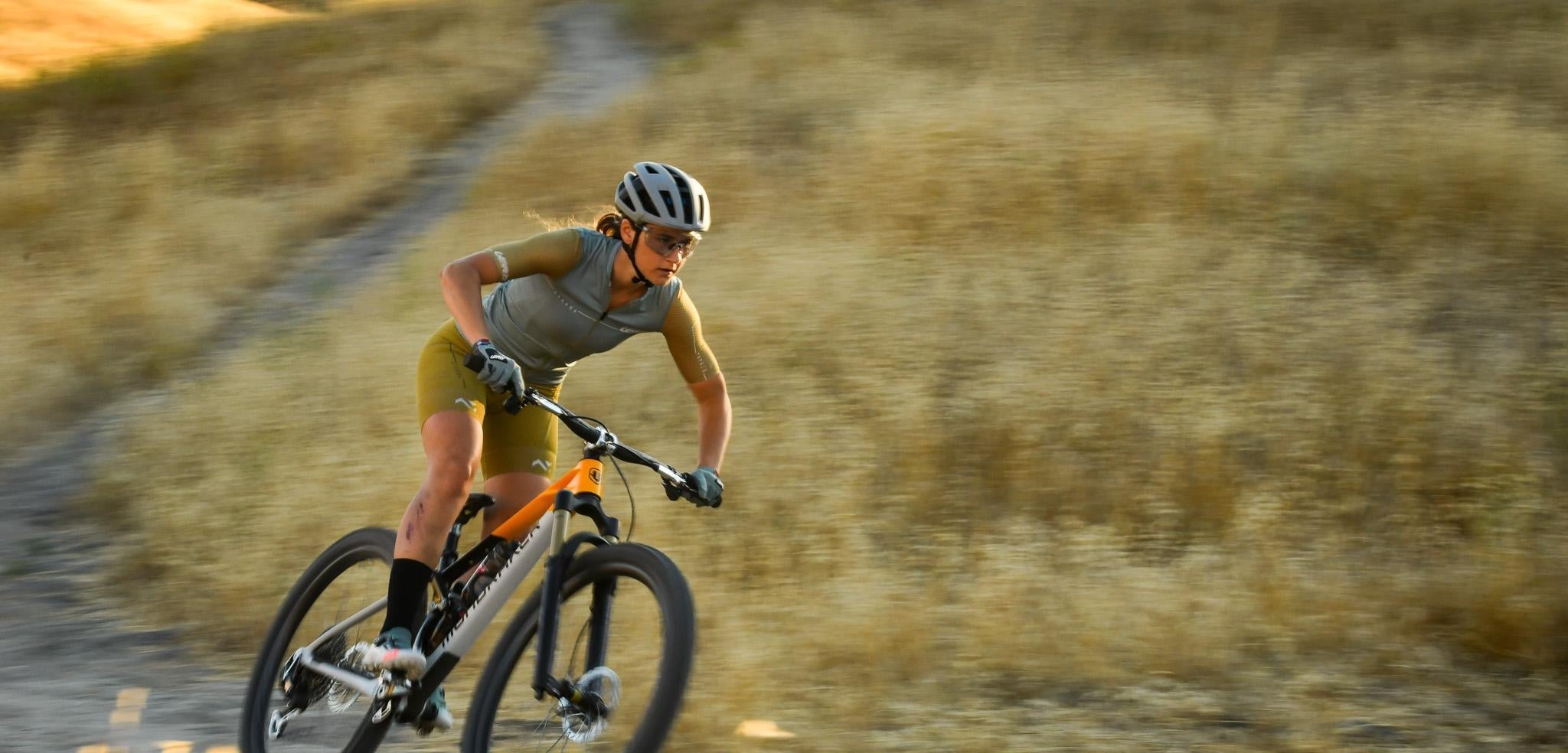Person riding a bicycle on a dirt path with a blurred background